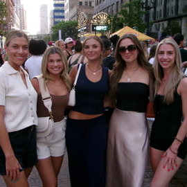 Hannah Curty with four friends on a busy city street during a lively outdoor festival